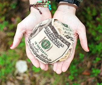 Hands holding crumpled hundred dollar bills outdoors