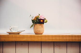 Minimalist coffee cup and flowers on wooden shelf