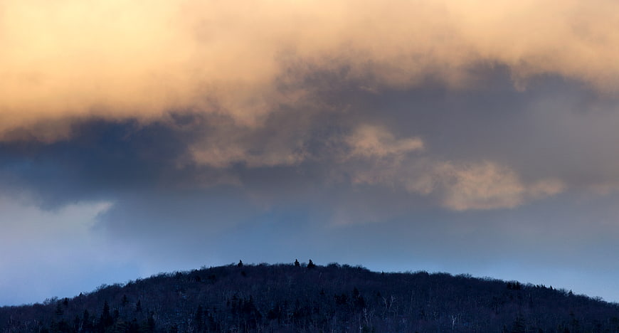 Dramatic Storm Clouds Over Silhouetted Mountain Ridge at Dusk