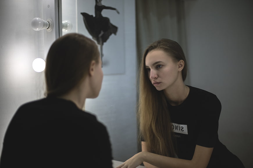 Young woman looking at reflection in dressing room mirror