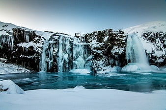 Frozen waterfall in Iceland with turquoise river and snow