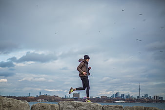 Woman jogging on rocks with Toronto skyline background