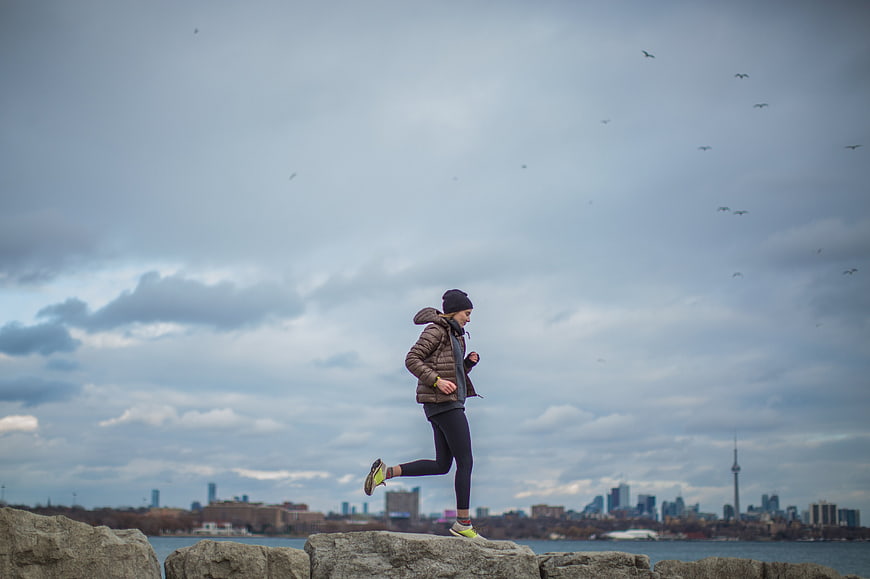 Woman jogging on rocks with Toronto skyline background