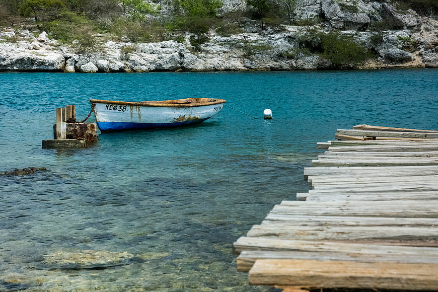 Weathered wooden boat moored near rustic pier in turquoise water
