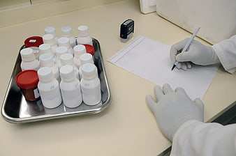 Lab technician writing notes next to chemical bottles