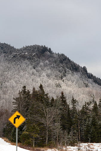 Yellow Curve Warning Sign on Snowy Mountain Road