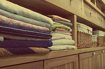 Stacked colorful towels on wooden shelves in linen closet