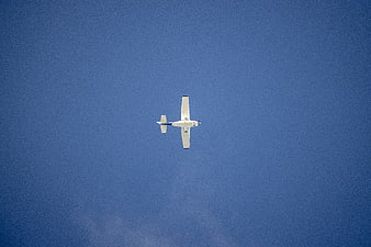 Small white airplane flying in clear blue sky