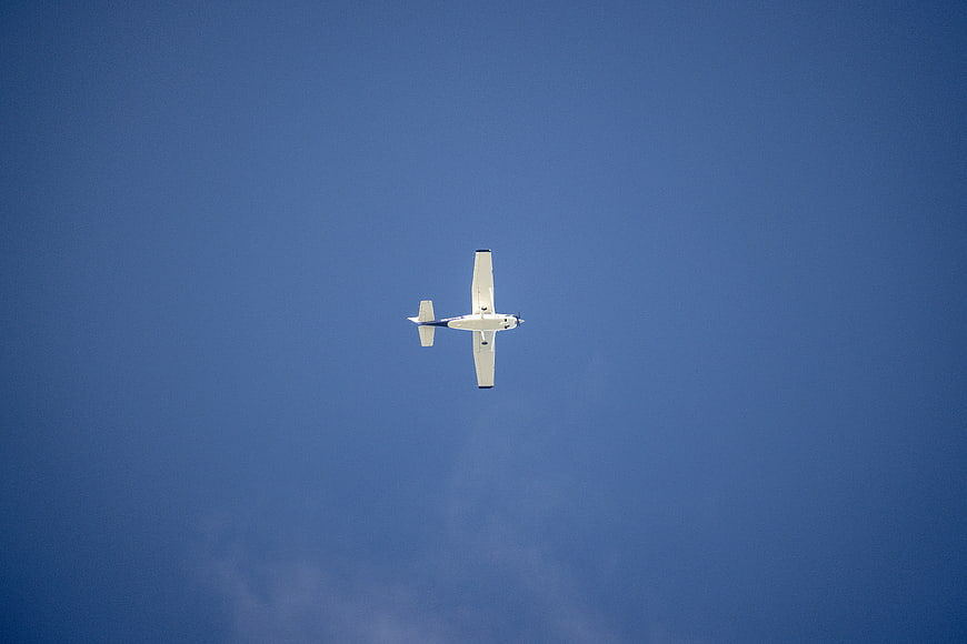 Small white airplane flying in clear blue sky