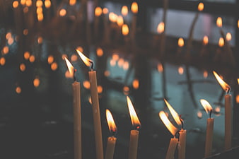 Close-up of lit prayer candles in a dark church interior
