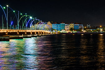 Colorful illuminated bridge and waterfront buildings at night in Curacao