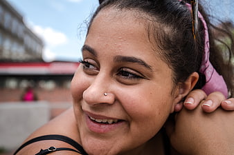 Close-up portrait of smiling woman with nose piercing outdoors