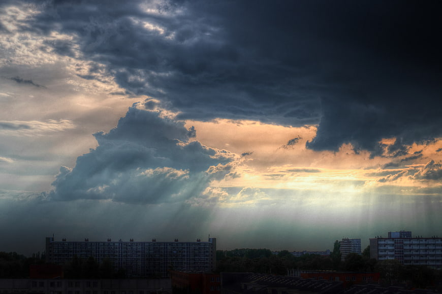 Dramatic storm clouds with sun rays over city skyline