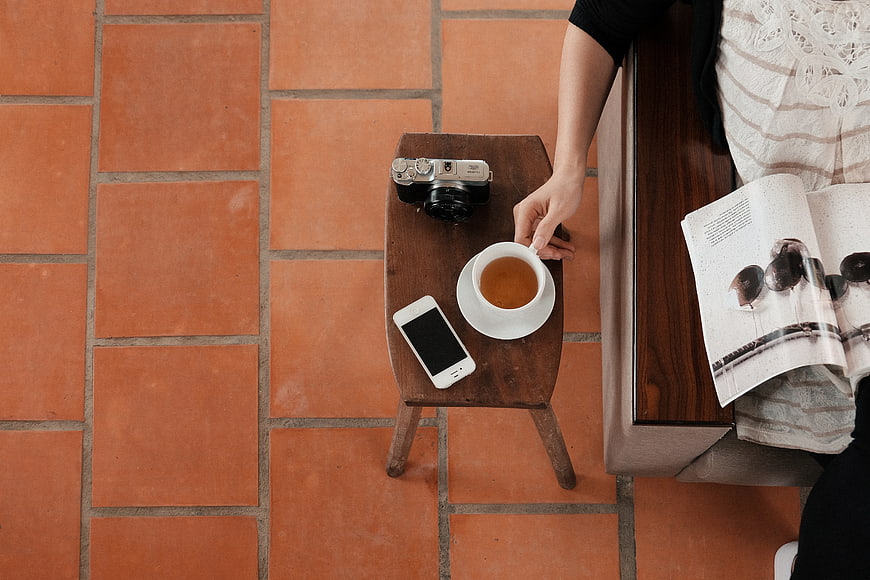 Top view of coffee, vintage camera, and smartphone on wooden stool