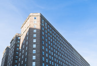 Low angle view of modern brick apartment building against blue sky