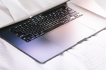 Close-up of silver laptop keyboard on white textured blanket