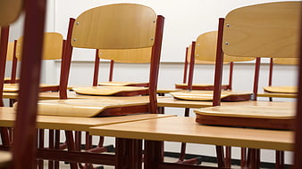 Empty wooden school chairs and desks in classroom