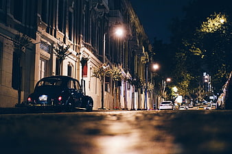 Vintage black car parked on quiet city street at night