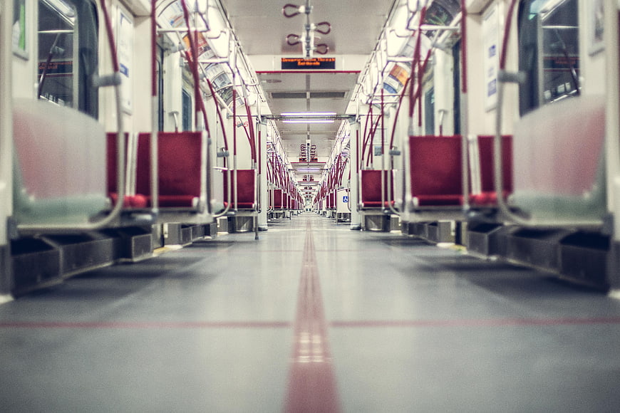 Empty subway car interior with red seats and leading lines