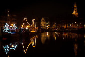 Night view of illuminated boats and church tower on a canal in Groningen, Netherlands