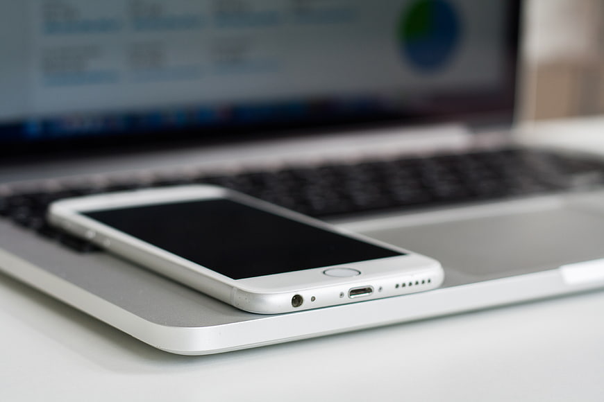 White Smartphone on Silver Laptop Keyboard Close Up
