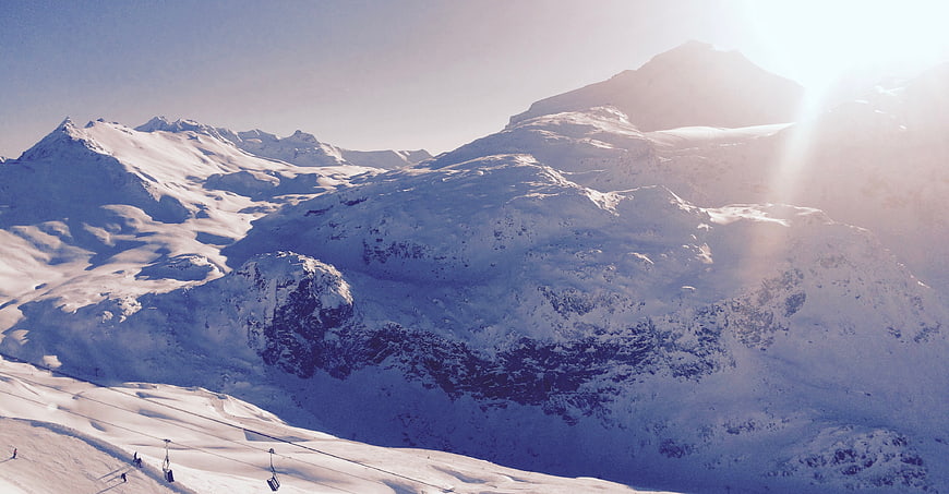 Snowy Mountain Landscape with Ski Lift and Sun Flare