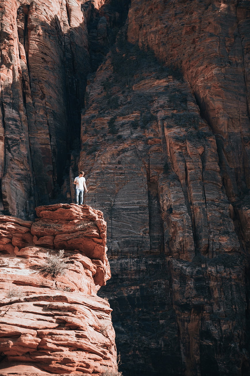 Man standing on red rock cliff edge in deep canyon
