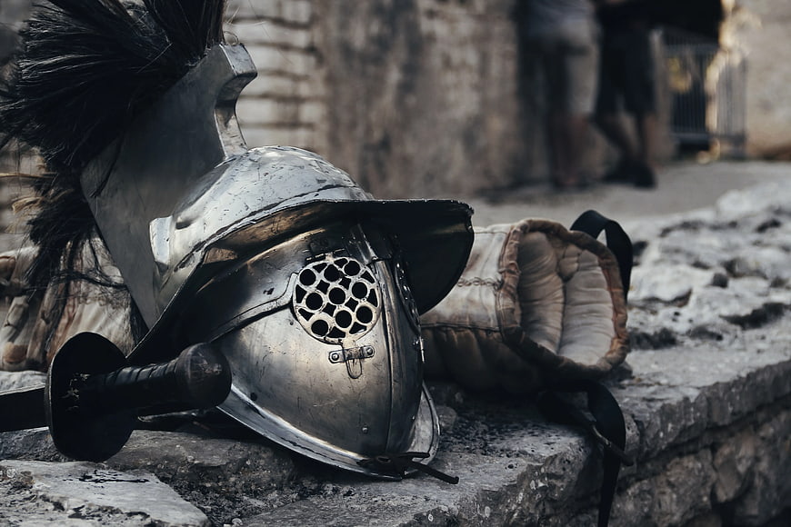 Close-up of silver medieval knight helmet with plume on stone