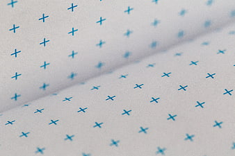 Close-up of white paper with blue plus sign pattern