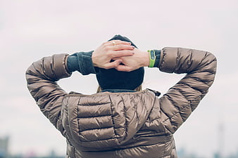 Woman in brown puffer jacket with hands behind head