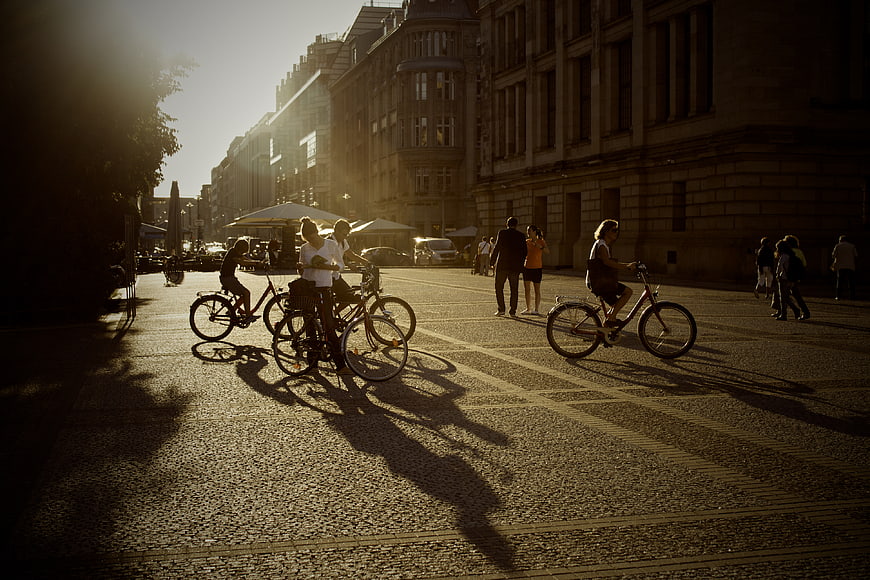 Cyclists and Pedestrians on Cobblestone Street at Golden Hour