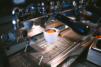 Espresso pouring from machine into white cup