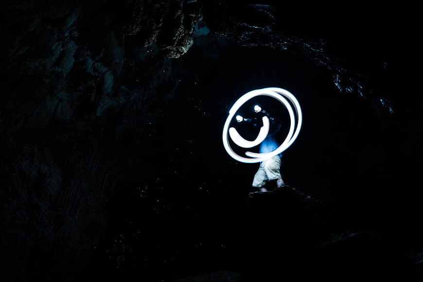 Light painting smiley face in dark cave at night