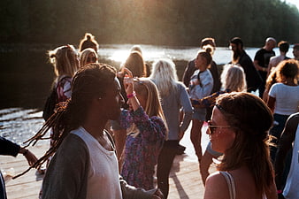 Diverse group of young people partying on a wooden dock at sunset