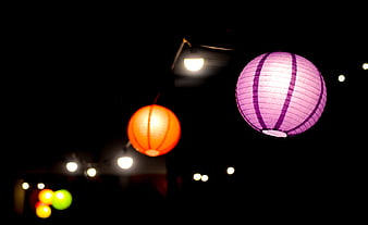 Illuminated purple and orange paper lanterns hanging at night
