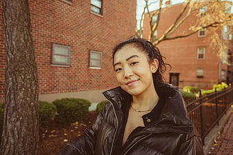 Portrait of smiling Asian woman in black puffer jacket outdoors
