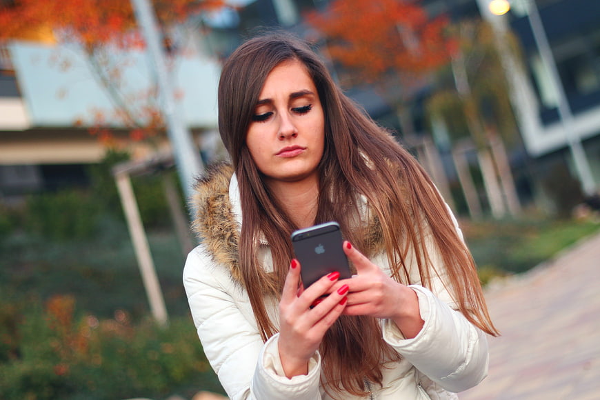 Young Woman Looking at Smartphone with Concerned Expression