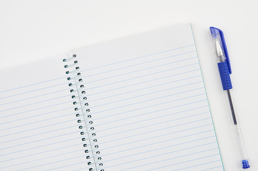 Blank spiral notebook and blue pen on white background