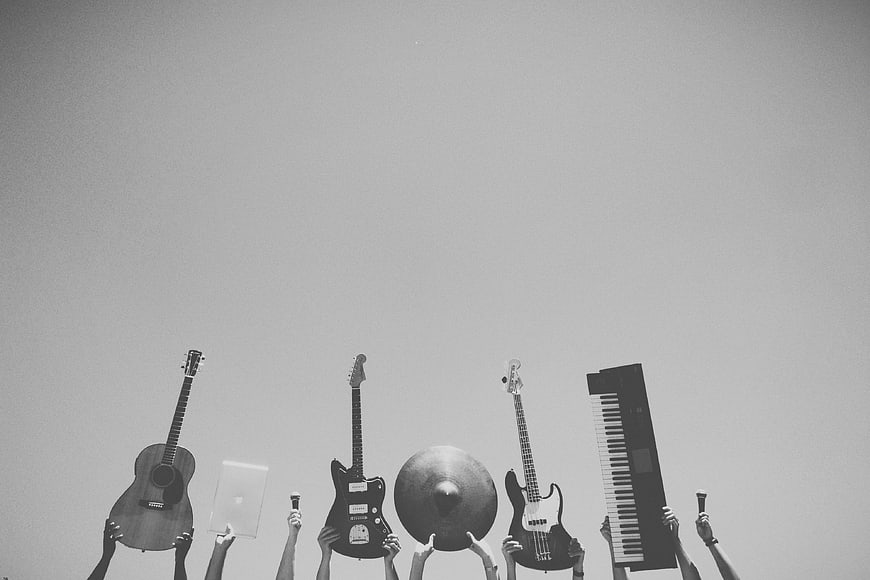 Black and white hands holding musical instruments against sky