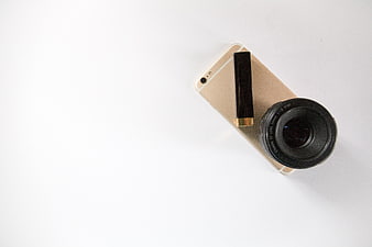 Minimalist flat lay of smartphone, camera lens, and lipstick on white background