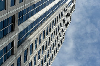 Low angle view of modern office building facade against blue sky