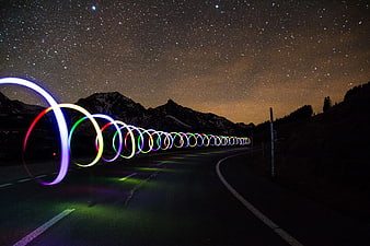 Colorful light painting rings on a mountain road at night