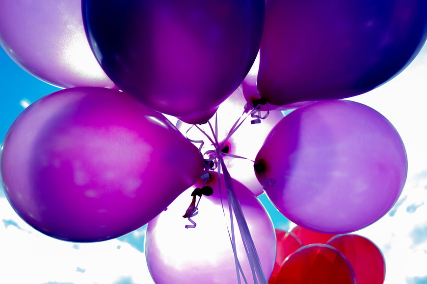 Vibrant purple and red balloons against a blue sky