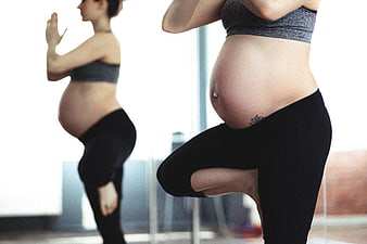Pregnant woman doing yoga in front of a mirror