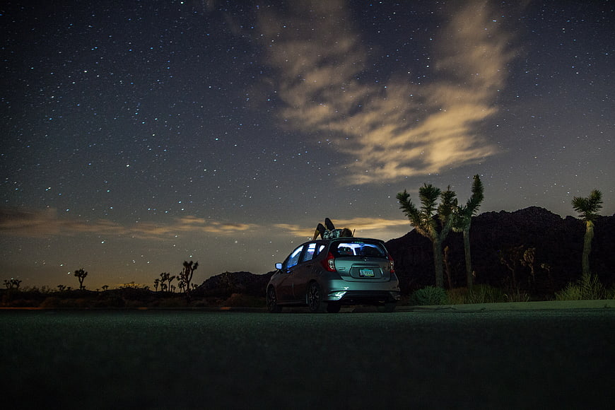 Couple Relaxing on Car Roof Under Starry Night Sky