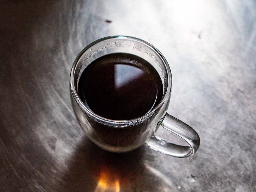 Top View of Black Coffee in Clear Glass Mug on Metal Table