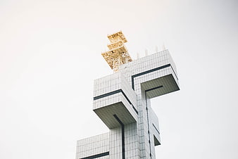 Modern geometric architecture with yellow lattice tower against white sky