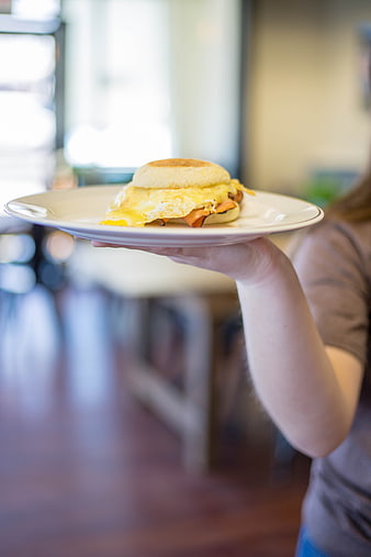 Waitress holding breakfast sandwich on white plate