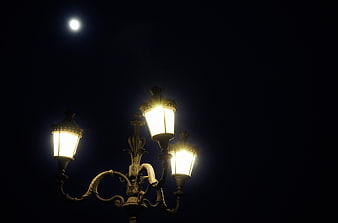 Vintage street lamp glowing under the moon at night