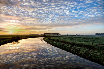 Serene River Landscape at Sunrise with Cloud Reflections